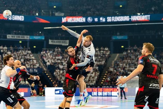 Lukas Jorgensen ( 25; SG Flensburg-Handewitt) springt zum Wurf und wird dabei von einem Spieler der MT Melsungen geblockt. Adrián Sipos ( 8; MT Melsungen) ist im Hintergrund links zu erkennen, rechts steht David Mandic ( 7; MT Melsungen). MT Melsungen vs SG Flensburg-Handewitt – EHF Finals Hamburg 2026 Copyright: xPhilippHeistx