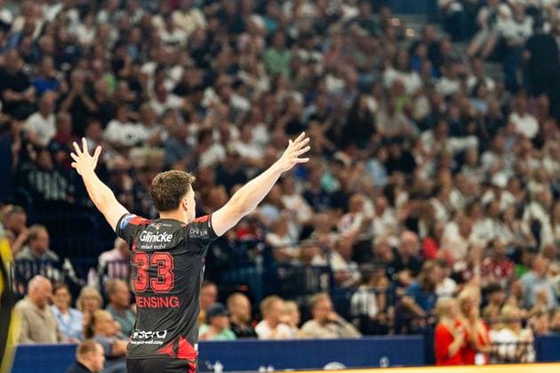 Aaron Mensing ( 33; MT Melsungen) reißt beide Arme in die Höhe und jubelt vor der vollbesetzten Tribüne. Der Rückraumspieler steht mit dem Rücken zur Kamera und feiert mit den Fans. MT Melsungen vs SG Flensburg-Handewitt – EHF Finals Hamburg 2026 Copyright: xPhilippHeistx