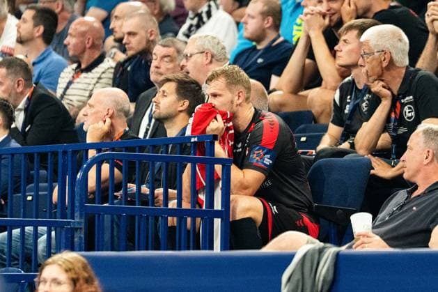 Ein Spieler der MT Melsungen sitzt auf der Auswechselbank und beobachtet das Spielgeschehen, ein Handtuch vor dem Gesicht haltend. Im Hintergrund sind Zuschauer und weitere Personen mit MT-Melsungen-Akkreditierungen zu sehen. MT Melsungen vs SG Flensburg-Handewitt – EHF Finals Hamburg 2026 Copyright: xPhilippHeistx