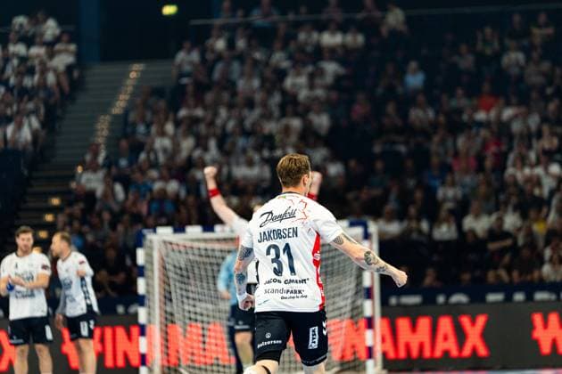 Emil Jakobsen ( 31; SG Flensburg-Handewitt) reißt beide Fäuste in die Höhe und feiert einen Treffer vor ausverkauftem Haus. Im Hintergrund sind zwei Mitspieler der SG Flensburg-Handewitt sowie das Tor zu sehen. MT Melsungen vs SG Flensburg-Handewitt – EHF Finals Hamburg 2026 Copyright: xPhilippHeistx