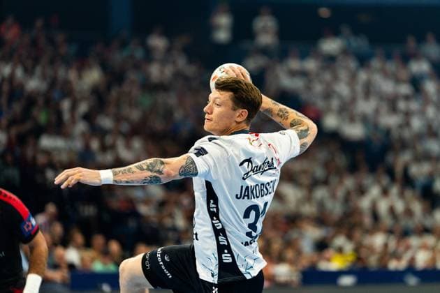 Emil Jakobsen ( 31; SG Flensburg Handewitt) holt mit dem Ball in der erhobenen Wurfhand aus und springt dabei ab. Im Hintergrund ist eine gut gefüllte Zuschauertribüne zu sehen. MT Melsungen vs SG Flensburg-Handewitt – EHF Finals Hamburg 2026 Copyright: xPhilippHeistx