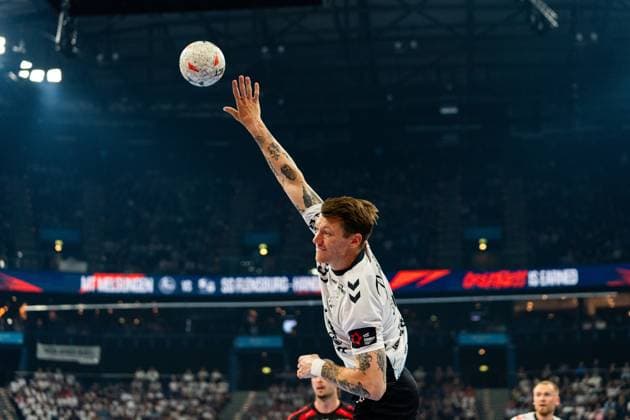 Emil Jakobsen ( 31; SG Flensburg Handewitt) springt hoch und wirft den Ball in Richtung Tor. Im Hintergrund sind weitere Spieler sowie die Anzeigetafel mit dem Spielpaarung MT Melsungen vs. SG Flensburg Handewitt zu sehen. MT Melsungen vs SG Flensburg-Handewitt – EHF Finals Hamburg 2026 Copyright: xPhilippHeistx