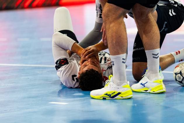 Ein Spieler der SG Flensburg-Handewitt liegt schmerzverzerrt auf dem Hallenboden und hält sich das Gesicht. Ein Spieler von MT Melsungen kniet neben ihm und stützt ihn. MT Melsungen vs SG Flensburg-Handewitt – EHF Finals Hamburg 2026 Copyright: xPhilippHeistx