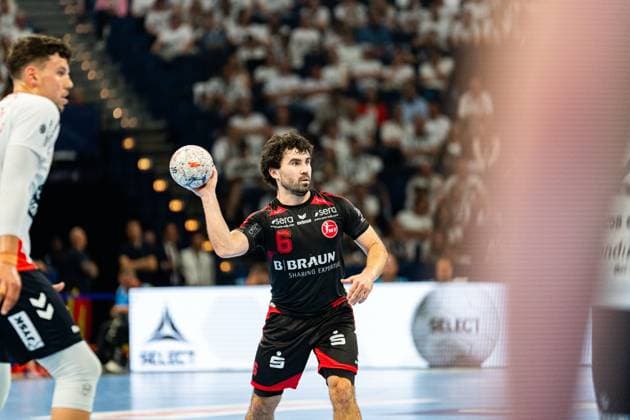 Erik Balenciaga ( 6; MT Melsungen) bereitet einen Wurf vor und hält den Ball in der rechten Hand. Im Hintergrund ist ein Spieler der SG Flensburg-Handewitt zu sehen. MT Melsungen vs SG Flensburg-Handewitt – EHF Finals Hamburg 2026 Copyright: xPhilippHeistx