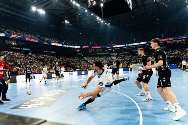 Ein Spieler von Montpellier HB wirft sich beim 3rd Place Match in einer Fallwurfbewegung nach vorne, während Domen Novak ( 63; SG Flensburg Handewitt) und ein weiterer Flensburg-Spieler in der Abwehr stehen. Im Hintergrund ist die vollbesetzte Arena mit dem Spielstand 10 auf der Anzeigetafel zu sehen. Domen Novak ( 63; SG Flensburg Handewitt) im Spiel gegen Montpellier HB Copyright: xPhilippHeistx
