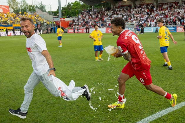 Jermain Nischalke (FC Würzburger Kickers) verfolgt Trainer Michael Schiele (Würzburger Kickers) wild mit einem vollen Bierglas in der Hand, um ihn nach dem Aufstieg in die 3. Liga im Rahmen des Sieges gegen Lok Leipzig traditionell mit Bier zu duschen, AKON Arena am Dallenberg, Würzburg, Deutschland, am 1. Juni 2026. DFB DFL REGULATIONS PROHIBIT ANY USE OF PHOTOGRAPHS AS IMAGE SEQUENCES AND OR QUASI-VIDEO, Copyright: HMBxMedia xHeikoxBecker