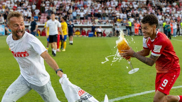 Jermain Nischalke (FC Würzburger Kickers) verfolgt Trainer Michael Schiele (Würzburger Kickers) wild mit einem vollen Bierglas in der Hand, um ihn nach dem Aufstieg in die 3. Liga im Rahmen des Sieges gegen Lok Leipzig traditionell mit Bier zu duschen, AKON Arena am Dallenberg, Würzburg, Deutschland, am 1. Juni 2026. DFB DFL REGULATIONS PROHIBIT ANY USE OF PHOTOGRAPHS AS IMAGE SEQUENCES AND OR QUASI-VIDEO, Copyright: HMBxMedia xHeikoxBecker