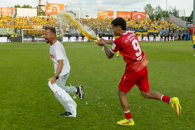 Jermain Nischalke (FC Würzburger Kickers) schüttet Trainer Michael Schiele das Bierglas triumphierend über den Kopf, um ihn nach dem erfolgreichen Aufstieg in die 3. Liga traditionell zu duschen. Der Trainer nimmt die humorvolle Aktion mit großer Freude an, AKON Arena am Dallenberg, Würzburg, Deutschland, am 1. Juni 2026. DFB DFL REGULATIONS PROHIBIT ANY USE OF PHOTOGRAPHS AS IMAGE SEQUENCES AND OR QUASI-VIDEO, Copyright: HMBxMedia xHeikoxBecker