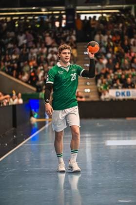 Handball, HBL, Frisch Auf! Göppingen - TVB 1898 Stuttgart Ein Spieler von Frisch Auf! Göppingen mit der Rückennummer 28 steht auf dem Spielfeld und hält den Handball zum Wurf erhoben. Im Hintergrund ist eine gut gefüllte Zuschauertribüne zu sehen. Frisch Auf! Göppingen Spieler ( 28) beim Wurfansatz