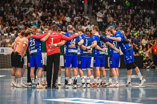 Handball, HBL, Frisch Auf! Göppingen - TVB 1898 Stuttgart Die Spieler des TVB Stuttgart bilden einen Mannschaftskreis auf dem Spielfeld, darunter erkennbar 25 (Zieker), 34, 3, 15 und 57. Im Kreis ist auch ein Spieler von Frisch Auf! Göppingen in grünem Trikot sowie der Torwart in rotem Trikot zu sehen. TVB Stuttgart Mannschaftskreis vor ausverkauftem Publikum