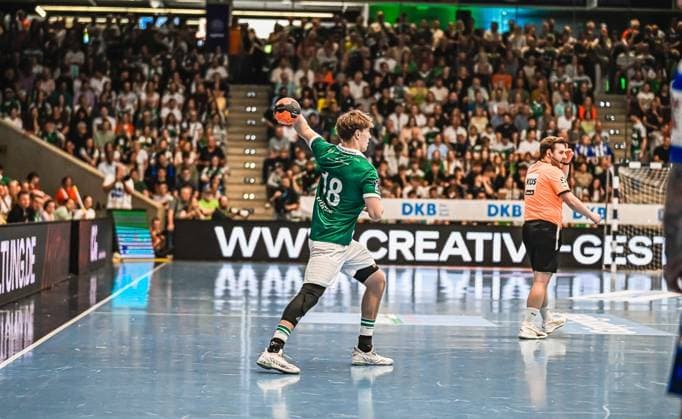 Handball, HBL, Frisch Auf! Göppingen - TVB 1898 Stuttgart #2 Ein Spieler von Frisch Auf! Göppingen mit der Nummer 18 holt zum Wurf aus, während der gegnerische Torwart im orangefarbenen Trikot die Position bezieht. Die vollbesetzte Arena bildet die Kulisse für diese Spielszene. Spieler ( 18; Frisch Auf! Göppingen) beim Wurf vor vollem Haus