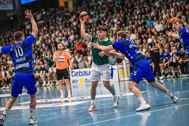 Handball, HBL, Frisch Auf! Göppingen - TVB 1898 Stuttgart #3 Elias Newel ( 40; Frisch Auf! Göppingen) zieht zum Wurf auf, während Ivan Snajder ( 10; TVB Stuttgart) links blockt und ein weiterer TVB-Verteidiger den Abschluss zu stören versucht. Im Hintergrund verfolgen zahlreiche Zuschauer die Szene in einer voll besetzten Halle. Elias Newel ( 40; Frisch Auf! Göppingen) beim Wurf gegen TVB Stuttgart