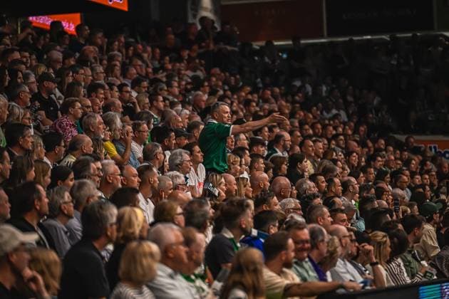 Handball, HBL, Frisch Auf! Göppingen - TVB 1898 Stuttgart #3 Ein Spieler von Frisch Auf! Göppingen im grünen Trikot steht vor der vollbesetzten Zuschauertribüne und streckt den Arm aus. Die Halle ist mit zahlreichen Fans gefüllt. Frisch Auf! Göppingen Spieler gestikuliert vor voller Tribüne