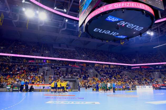 Handball, HBL, Rhein-Neckar Löwen - TSV Hannover-Burgdorf #4 Totale der SAP Arena in Mannheim während einer Spielunterbrechung: Die Rhein Neckar Löwen (gelbe Trikots) stehen in einer Auszeit-Besprechung auf dem Spielfeld, während die TSV Hannover-Burgdorf-Spieler (grüne Torwarttrikots sichtbar) auf der rechten Seite stehen. Die Halle ist gut gefüllt mit überwiegend gelb gekleideten Heimfans. Auszeit in der SAP Arena beim Spiel Rhein Neckar Löwen gegen TSV Hannover-Burgdorf