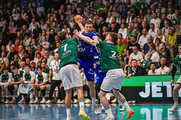 Handball, HBL, Frisch Auf! Göppingen - TVB 1898 Stuttgart #5 Simone Mengon ( 15; TVB Stuttgart) springt zum Wurf und wird von Victor Klöve ( 7; Frisch Auf! Göppingen) und Oskar Neudeck ( 2; Frisch Auf! Göppingen) in die Zange genommen. Die Szene zeigt einen intensiven Zweikampf vor vollem Zuschauerrang. Simone Mengon ( 15; TVB Stuttgart) im Zweikampf gegen Frisch Auf! Göppingen