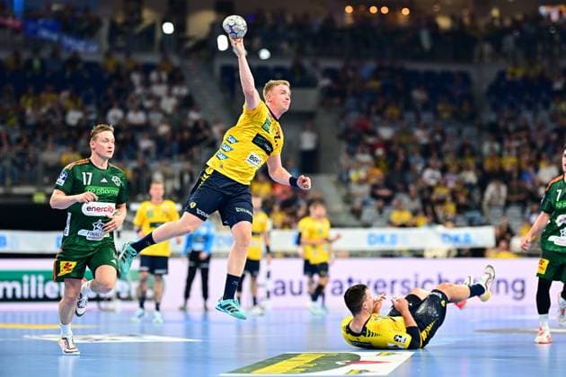 Handball, HBL, Rhein-Neckar Löwen - TSV Hannover-Burgdorf #6 Ein Spieler der Rhein Neckar Löwen springt hoch in die Luft und holt zum Wurf aus, während August Baskar Pedersen ( 17; TSV Hannover Burgdorf) im Hintergrund mitläuft. Ein weiterer Löwen-Spieler liegt auf dem Boden, ein Hannover-Spieler mit 7 ist am rechten Bildrand zu sehen. Rhein Neckar Löwen Spieler springt zum Wurf gegen August Baskar Pedersen ( 17; TSV Hannover Burgdorf) Copyright: xMichaelxGelhardtx