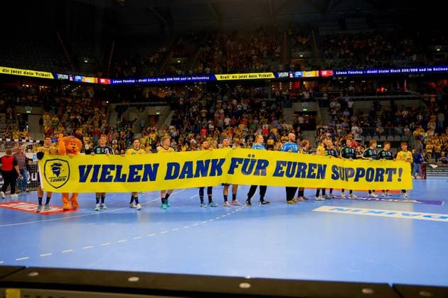 Handball, HBL, Rhein-Neckar Löwen - TSV Hannover-Burgdorf #4 Die Spieler der Rhein Neckar Löwen stehen nach dem Spiel gemeinsam mit dem Maskottchen auf dem Spielfeld und halten ein gelbes Banner mit der Aufschrift Vielen Dank für euren Support! . Im Hintergrund applaudieren die Zuschauer in der gut gefüllten Arena. Rhein Neckar Löwen bedanken sich mit Banner bei den Fans