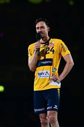 Patrick Groetzki ( 24; Rhein Neckar Löwen) steht im Spielertrikot mit einem Mikrofon in der Hand vor dunklem Hintergrund. Er hält ein Blatt Papier in der anderen Hand und spricht zu den Zuschauern. Patrick Groetzki ( 24; Rhein Neckar Löwen) spricht ins Mikrofon Copyright: xMichaelxGelhardtx