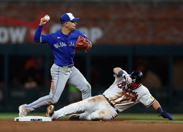 Shortstop Andres Gimenez 0 of the Toronto Blue Jays throws to first base as third baseman Austin Riley 27 of the Atlanta Braves slides into second base in the sixth inning at Truist Park on Wednesday, June 3, 2026 in Atlanta, Georgia.  ATL20260603114 MikexZarrilli