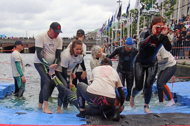 Ironman in Hamburg 2026: Helfer und Helferinnen betreuen einen Athlet, der nach dem Schwimmen Krämpfe in den Beinen bekommen hat.