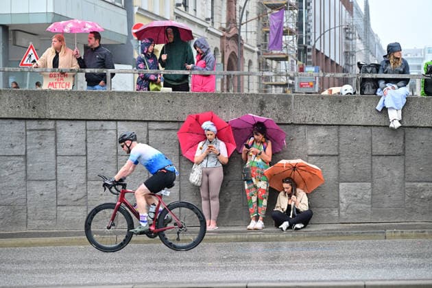 GER; Ironman Hamburg 07.06.2026, GER; Ironman Hamburg, Jedermaenner im Bild Feature Zuschauer mit Regenschirm und Radfahrer