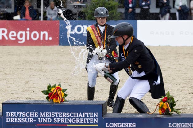 Isabell WERTH (GER, li.) mit der Sektflasche in der Hand mit Raphael NETZ (GER, re.) bei der Siegerehrung, Sektdusche, Freude, Jubel, Lachen, Dressur 03: Longines Grosser Optimum Preis, Deutsche Meisterschaften Grand Prix Kuer 2026, Dressur, Balve Deutschland, am 07.06.2026; Â