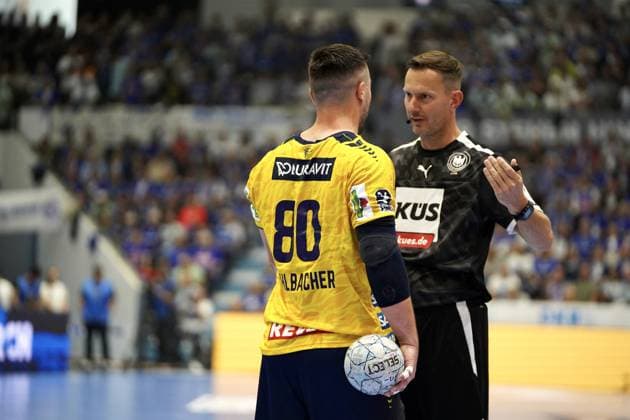 Jannik Kohlbacher ( 80; Rhein Neckar Löwen) steht mit dem Handball in der Hand und spricht mit dem Schiedsrichter in der SCHWALBE arena in Gummersbach. Der Schiedsrichter gestikuliert mit der Hand während der Unterhaltung. Jannik Kohlbacher ( 80; Rhein Neckar Löwen) im Gespräch mit Schiedsrichter