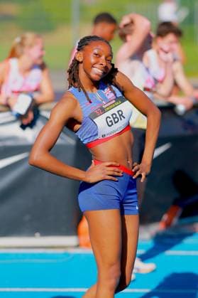 Eine Athletin aus Great Britain posiert lächelnd auf der Tartanbahn des Michael-Hoffmann-Stadions in Mannheim. Auf ihrer Startnummer ist GBR sowie der Schriftzug 32. Junioren-Gala Mannheim 2024 zu lesen. Athletin aus Great Britain bei der 32. Junioren-Gala in Mannheim