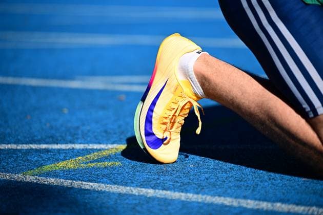 Ein gelber Nike-Sprintschuh mit blauem Swoosh-Logo liegt auf der blauen Tartanbahn des Michael-Hoffmann-Stadions in Mannheim. Die Startnummer des Athleten ist nicht lesbar, eine Personenidentifikation ist nicht möglich. Nahaufnahme eines Nike-Sprintschuhs auf der blauen Tartanbahn