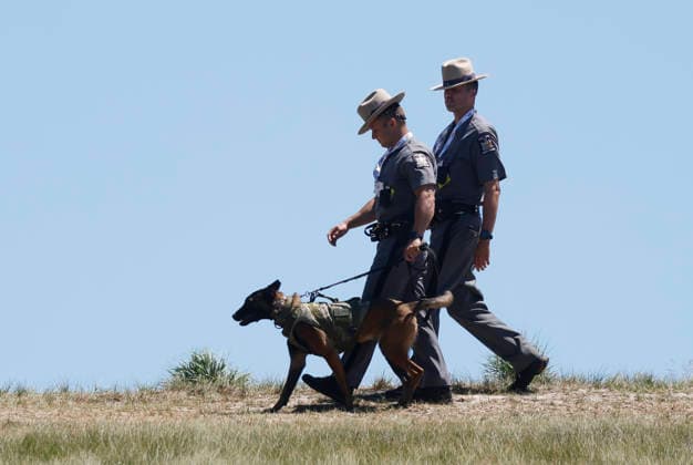 State Troopers walk with a police dog while players have a practice round on the Monday before the 126th U.S. Open Golf Championship at Shinnecock Hills Golf Club on Monday, June 15, 2026 in Southampton, New York.  NYP20260615318 JOHNxANGELILLO