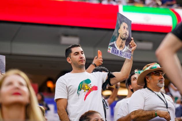 USA: Fußball FIFA World Cup, WM, Weltmeisterschaft, Fussball 2026 Gruppenphase Gruppe G Iran vs Neuseeland SoFi Stadium (Inglewood, Los Angeles County, Kalifornien): Ein iranischer Fan verfolgt das WM-Spiel von den Tribünen aus und hält ein Porträtfoto eines Fußballspielers mit der Aufschrift Iran Rising in die Höhe. Das Motiv verweist auf die Unterstützung der iranischen Opposition, die Protestbewegung und die politische Identität von Exil-Iranern. Die historische Löwen-und-Sonne-Symbolik gilt als Zeichen des Widerstands gegen die Islamische Republik.