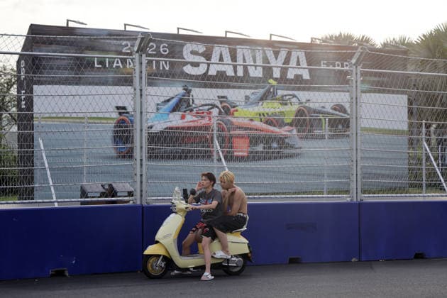 Zwie Jungendliche auf ihrem Elektroroller vor dem FE Wrebeplakat Kreuzung Fengtang- Haitang Nord Raod, Hainan Insel, China, FIA Formel E Weltmeisterschaft Saison 12, Sanya E-Prix, China, 17.06.2026, Teil der Rennstrecke, Vorbereitung
