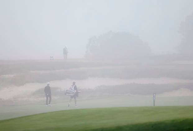 Alejandro Tosti of Argentina walks with his caddie as thick fog causes a delay in play during the first round of the 126th U.S. Open Golf Championship at Shinnecock Hills Golf Club in Southampton, NY, on Thursday, June 18, 2026.  NYC20260618801 JOHNxANGELILLO