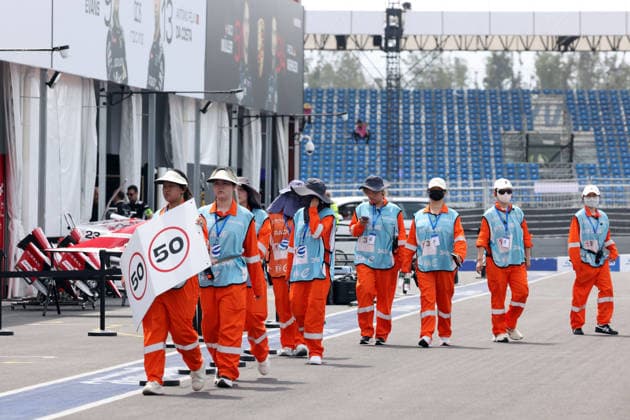 In Sonnenschutzkleidung eingehüllte Streckenpostinen gehe auf ihre Positionen in der Boxengasse, Sanya E-Prix, China, 19.06.2026, Hainan Insel, China, FIA Formel E Weltmeisterschaft Saison 12,