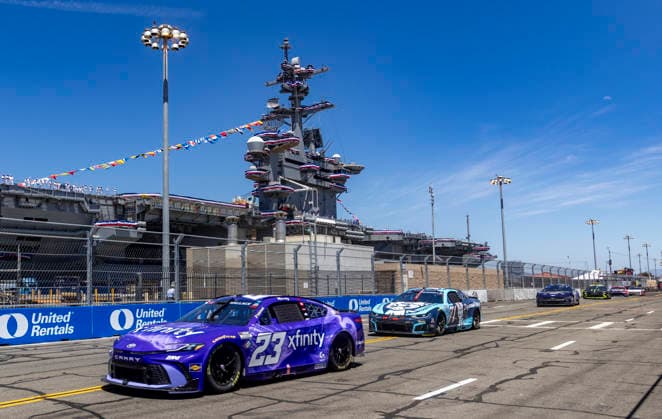 SAN DIEGO, CA - JUNE 21: Bubba Wallace of the 23 23XI Racing Xfinity Toyota among the field passing by the USS Carl Vinson (CVN70) during the Anduril 250 NASCAR, Motorsport, USA Cup Series Race, Sunday, June 21, 2026, at Naval Base Coronado in San Diego, California. (Photo by Tony Ding Icon Sportswire) AUTO: JUN 21 NASCAR Cup Series Anduril 250 Race the Base EDITORIAL USE ONLY Icon46520260621027250