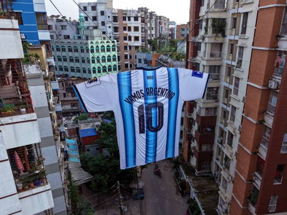 Sport Bilder des Tages June 22, 2026, Dhaka, Bangladesh: A giant Argentina national football team jersey dedicated to Lionel Messi hangs between two residential buildings in the Ibrahimpur neighborhood of Dhaka, Bangladesh. Measuring approximately 40 feet by 30 feet, the replica jersey is believed by local supporters to be the largest fan-made Argentina jersey in South Asia. Football fever regularly sweeps across Bangladesh during FIFA World Cup, WM, Weltmeisterschaft, Fussball tournaments, with passionate supporters of Argentina, Brazil and other football nations decorating neighborhoods with flags, banners and oversized displays in celebration of the Bangladesh: Massive Argentina Jersey Draws Attention In Dhaka  - ZUMAk174 20260622_zip_k174_004 Copyright: xSyedxMahabubulxKaderx