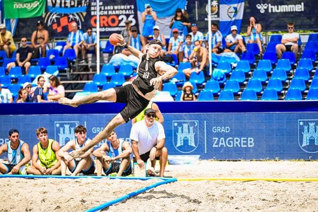 Oliver Middell ( 20; Deutschland Beachhandball Nationalmannschaft) springt weit über die Feldlinie und zieht zum Wurf ab. Im Hintergrund verfolgen Zuschauer und Bankspieler die Aktion beim IHF Beach Handball World Championship, WM, Weltmeisterschaft am Jarun See in Zagreb. IHF Beach Handball World Championship 2026, 23.06.2026, Zagreb, Jarun See *** Oliver Middell 20 Copyright: xspeedshotx xDorianfrickx