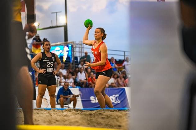 Eine Spielerin im roten Torwarttrikot holt zum Wurf aus, während eine uruguayische Gegenspielerin ( 29, URU) im Hintergrund beobachtet. Das Spiel findet am Jarun See in Zagreb vor gut gefüllten Tribünen statt. IHF Beach Handball World Championship, WM, Weltmeisterschaft 2026, 23.06.2026, Zagreb, Jarun See *** A player in a red goalkeeper jersey winds up to take a shot, while a Uruguayan opponent (No. 29, URU) watches from the background. The game is taking place at Lake Jarun in Zagreb in front of a packed crowd. 2026 IHF Beach Handball World Championship, June 23, 2026, Zagreb, Lake Jarun,detected_source_language Copyright: xspeedshotx xDorianfrickx