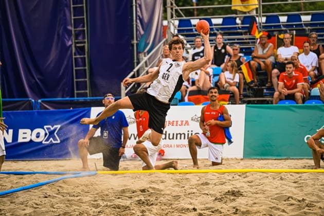 Lennart Wörmann ( 2; Deutschland Beachhandball Nationalmannschaft) springt dynamisch ab und holt zum Wurf aus, der Ball ist klar in seiner erhobenen Hand sichtbar. Im Hintergrund verfolgen Zuschauer mit deutschen Fahnen die Szene am Jarun See in Zagreb. IHF Beach Handball World Championship, WM, Weltmeisterschaft 2026, 23.06.2026, Zagreb, Jarun See *** Lennart Wörmann 2, a member of the German national beach handball team, takes off dynamically and winds up for a shot; the ball is clearly visible in his raised hand. In the background, spectators waving German flags watch the action at Lake Jarun in Zagreb during the 2026 IHF Beach Handball World Championship, June 23, 2026, Zagreb, Lake Jarun,detected_source_language Copyright: xspeedshotx xDorianfrickx