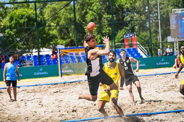 Ein Spieler der deutschen Beachhandball-Nationalmannschaft springt zum Wurf und hält den Ball hoch über dem Kopf, während ein Gegenspieler in gelb-grünem Trikot versucht zu blocken. Im Hintergrund ist ein weiterer deutscher Spieler ( 6 ZELSER Lars) zu sehen. IHF Beach Handball World Championship, WM, Weltmeisterschaft 2026, 23.06.2026, Zagreb, Jarun See *** A player on the German national beach handball team jumps to shoot, holding the ball high above his head, while an opponent in a yellow-and-green jersey tries to block the shot. In the background, another German player, Lars ZELSER, can be seen. IHF Beach Handball World Championship 2026, June 23, 2026, Zagreb, Lake Jarun,detected_source_language Copyright: xspeedshotx xDorianfrickx