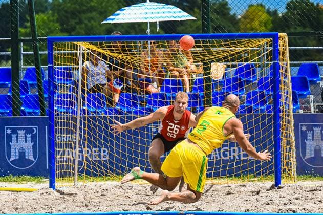 Moritz Ebert ( 26; Deutschland Beachhandball Nationalmannschaft) wirft sich im Tor dem Ball entgegen, während ein Angreifer Brasiliens in gelb-grünem Trikot den Abschluss versucht. Die Szene findet am Jarun See in Zagreb im Sand statt. IHF Beach Handball World Championship, WM, Weltmeisterschaft 2026, 23.06.2026, Zagreb, Jarun See *** Moritz Ebert, 26, of the German national beach handball team, dives toward the ball in the goal while a Brazilian attacker in a yellow-and-green jersey attempts a shot. The scene takes place on the sand at Lake Jarun in Zagreb during the 2026 IHF Beach Handball World Championship, June 23, 2026, Zagreb, Lake Jarun,detected_source_language Copyright: xspeedshotx xDorianfrickx