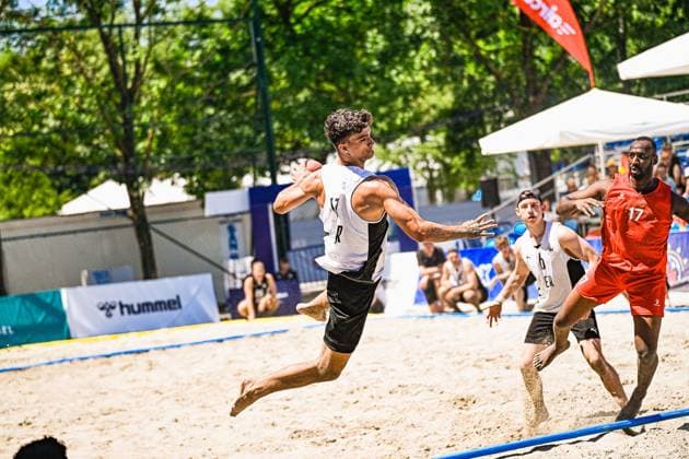 Ein Spieler der deutschen Beachhandball-Nationalmannschaft springt barfuß über den Sand und holt zum Wurf aus. Im Hintergrund verfolgt ein Gegner in rotem Trikot ( 17) die Aktion beim Turnier am Jarun See in Zagreb. IHF Beach Handball World Championship, WM, Weltmeisterschaft 2026, 23.06.2026, Zagreb, Jarun See *** A player on the German national beach handball team jumps barefoot across the sand and winds up to shoot. In the background, an opponent in the red jersey numbered 17 watches the action at the tournament on Lake Jarun in Zagreb during the 2026 IHF Beach Handball World Championship, June 23, 2026, Zagreb, Lake Jarun Copyright: xspeedshotx xDorianfrickx