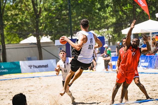 Tim Krauth ( 17; Deutschland Beachhandball Nationalmannschaft) springt im Sand ab und zieht zum Wurf hoch, während ein Gegenspieler in Rot die Arme hebt. Im Hintergrund läuft ein weiterer deutscher Spieler mit der Nummer 6 ins Bild. IHF Beach Handball World Championship, WM, Weltmeisterschaft 2026, 23.06.2026, Zagreb, Jarun See *** Tim Krauth, 17, of the German national beach handball team, takes off from the sand and rises to take a shot, while an opponent in red raises his arms. In the background, another German player, number 6, runs into the frame. IHF Beach Handball World Championship 2026, June 23, 2026, Zagreb, Lake Jarun Copyright: xspeedshotx xDorianfrickx