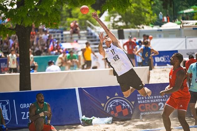 Tim Krauth ( 17; Deutschland Beachhandball Nationalmannschaft) springt hoch und wirft den Ball in einer spektakulären Aktion beim IHF Beach Handball World Championship, WM, Weltmeisterschaft am Jarun See in Zagreb. Ein Gegenspieler in roten Trikots beobachtet die Szene von der Seite. IHF Beach Handball World Championship 2026, 23.06.2026, Zagreb, Jarun See *** Tim Krauth, 17, of the German national beach handball team, jumps high and throws the ball in a spectacular play during the IHF Beach Handball World Championship at Lake Jarun in Zagreb. An opponent in a red jersey watches the scene from the sidelines. IHF Beach Handball World Championship 2026, June 23, 2026, Zagreb, Lake Jarun Copyright: xspeedshotx xDorianfrickx