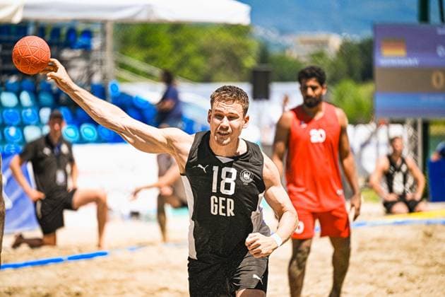 Robin John ( 18; Deutschland Beachhandball Nationalmannschaft) holt mit dem Ball in der erhobenen Hand zum Wurf aus. Im Hintergrund ist ein Gegenspieler im roten Trikot mit der Nummer 20 zu sehen. IHF Beach Handball World Championship, WM, Weltmeisterschaft 2026, 23.06.2026, Zagreb, Jarun See *** Robin John 18, a member of the German national beach handball team, prepares to shoot with the ball held aloft. In the background, an opponent in a red jersey with the number 20 can be seen. IHF Beach Handball World Championship 2026, June 23, 2026, Zagreb, Lake Jarun Copyright: xspeedshotx xDorianfrickx