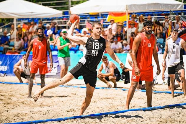 Robin John ( 18; Deutschland Beachhandball Nationalmannschaft) zieht im Sprung zum Wurf ab, Sand spritzt unter seinen Füßen auf. Im Hintergrund verfolgen Zuschauer mit deutschen Fahnen das Spiel am Jarun See in Zagreb. IHF Beach Handball World Championship, WM, Weltmeisterschaft 2026, 23.06.2026, Zagreb, Jarun See *** Robin John, 18, of the German national beach handball team, jumps to take a shot; sand sprays up from under his feet. In the background, spectators waving German flags watch the game at Lake Jarun in Zagreb during the 2026 IHF Beach Handball World Championship, June 23, 2026, Zagreb, Lake Jarun Copyright: xspeedshotx xDorianfrickx