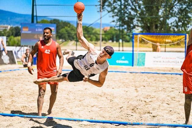 Lars Zelser ( 6; Deutschland Beachhandball Nationalmannschaft) führt einen spektakulären Drehwurf in der Luft aus, den Ball hoch über dem Kopf. Im Hintergrund beobachtet ein Gegenspieler in rotem Trikot mit der Nummer 42 die Aktion am Jarun See in Zagreb. IHF Beach Handball World Championship, WM, Weltmeisterschaft 2026, 23.06.2026, Zagreb, Jarun See *** Lars Zelser 6 of the German national beach handball team performs a spectacular spin shot in midair, with the ball high above his head. In the background, an opponent in a red jersey with the number 42 watches the action at Lake Jarun in Zagreb during the 2026 IHF Beach Handball World Championship, June 23, 2026, Zagreb, Lake Jarun Copyright: xspeedshotx xDorianfrickx