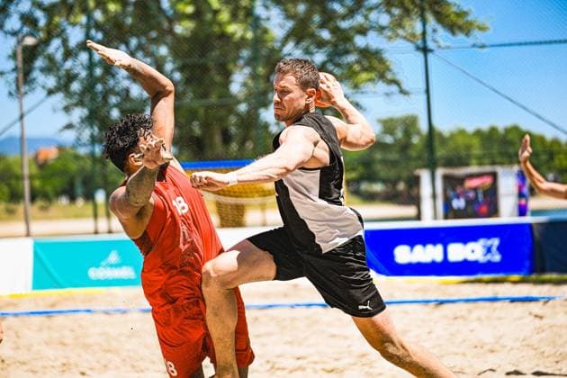 Ein Spieler der deutschen Beachhandball-Nationalmannschaft im schwarzen Trikot setzt zum Wurf an, während ein Gegenspieler im roten Trikot den Arm blockierend hochreißt. Die intensive Szene spielt sich im Sand am Jarun See in Zagreb ab. IHF Beach Handball World Championship, WM, Weltmeisterschaft 2026, 23.06.2026, Zagreb, Jarun See *** A player on the German national beach handball team, wearing a black jersey, prepares to shoot, while an opponent in a red jersey raises his arm to block the shot. This intense scene takes place on the sand at Lake Jarun in Zagreb during the 2026 IHF Beach Handball World Championship, June 23, 2026, Zagreb, Lake Jarun Copyright: xspeedshotx xDorianfrickx