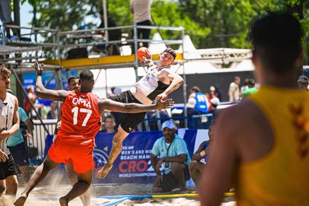 Ein Spieler der deutschen Beachhandball-Nationalmannschaft springt zum Wurf und hält den Ball hoch, während ein Oman-Spieler ( 17) mit ausgestrecktem Arm versucht zu blocken. Die Szene findet im Sand beim IHF Beach Handball World Championship, WM, Weltmeisterschaft am Jarun See in Zagreb statt. IHF Beach Handball World Championship 2026, 23.06.2026, Zagreb, Jarun See *** A player on the German national beach handball team jumps to shoot and holds the ball aloft, while an Omani player (No. 17) tries to block the shot with his arm outstretched. The scene takes place on the sand at the IHF Beach Handball World Championship at Lake Jarun in Zagreb. IHF Beach Handball World Championship 2026, June 23, 2026, Zagreb, Lake Jarun Copyright: xspeedshotx xDorianfrickx