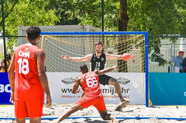 Oliver Middell ( 20; Deutschland Beachhandball Nationalmannschaft) steht im Tor und versucht einen Wurf des Gegners abzuwehren, während ein Spieler in rotem Trikot mit der Nummer 66 den Ball aus kurzer Distanz wirft. Im Vordergrund beobachtet ein weiterer Spieler in rotem Trikot ( 18) die Szene am Jarun See in Zagreb. IHF Beach Handball World Championship, WM, Weltmeisterschaft 2026, 23.06.2026, Zagreb, Jarun See *** Oliver Middell, No. 20 on the German national beach handball team, is in goal and trying to block a shot by an opponent, while a player in a red jersey with the number 66 shoots the ball from close range. In the foreground, another player in a red jersey with the number 18 watches the action at Lake Jarun in Zagreb. IHF Beach Handball World Championship 2026, June 23, 2026, Zagreb, Lake Jarun Copyright: xspeedshotx xDorianfrickx
